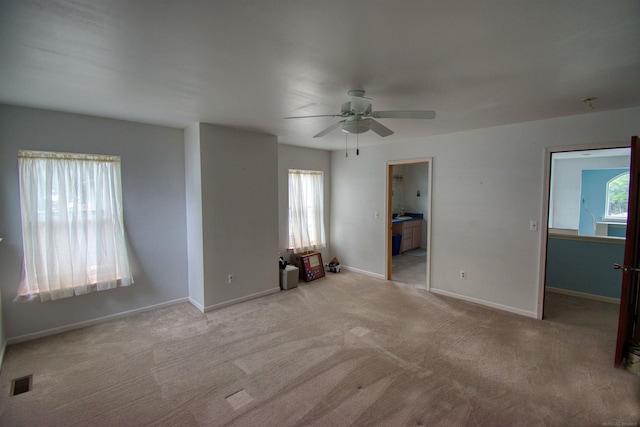 carpeted spare room featuring a healthy amount of sunlight and ceiling fan