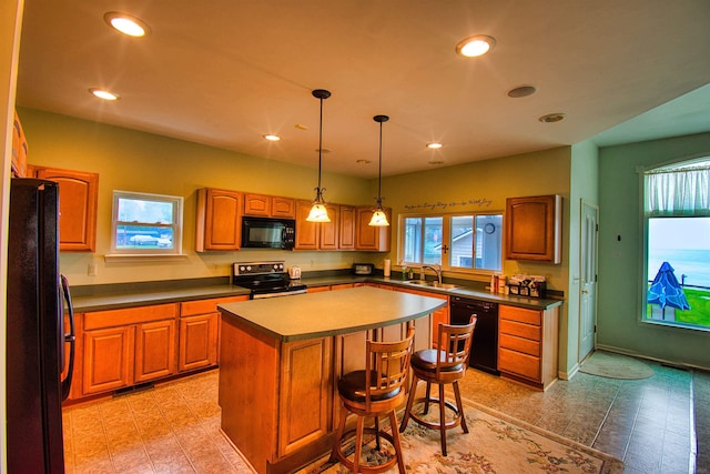 kitchen with a kitchen island, a breakfast bar, decorative light fixtures, sink, and black appliances