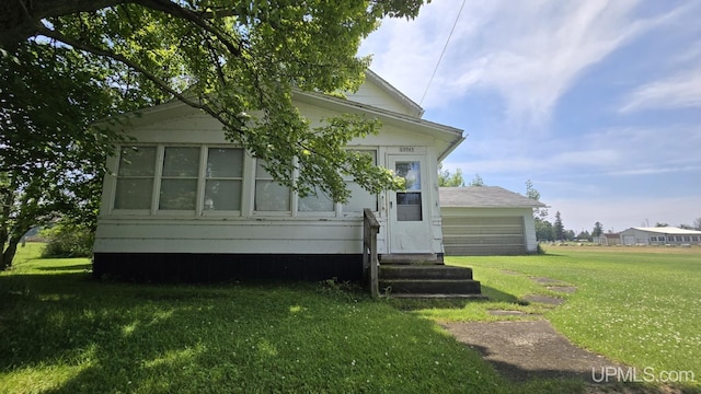 rear view of property featuring entry steps and a lawn