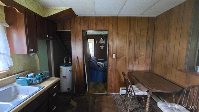 kitchen with water heater, wooden walls, sink, and a baseboard radiator