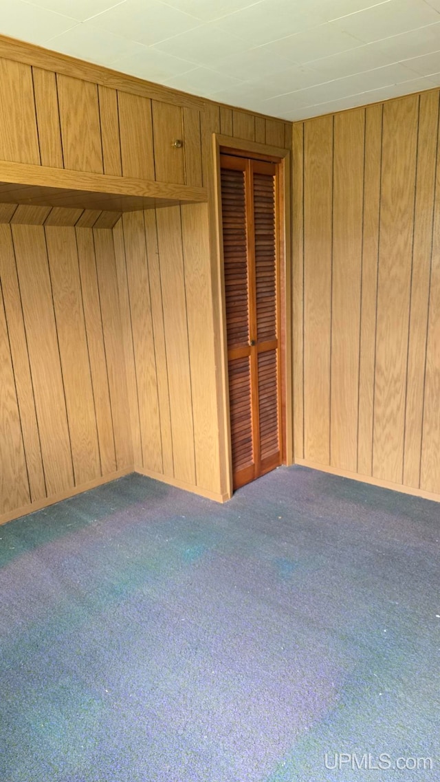 carpeted spare room with wood walls