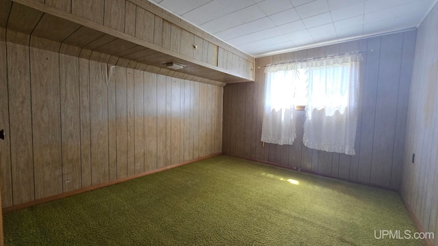 carpeted spare room with wooden walls