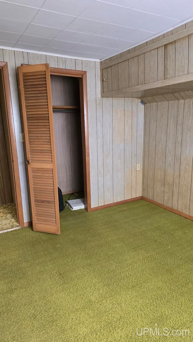 unfurnished bedroom with wood walls, a closet, and carpet flooring