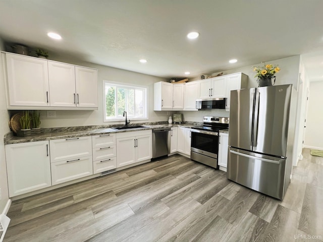 kitchen with sink, white cabinets, stainless steel appliances, and dark stone countertops