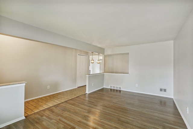 unfurnished room featuring a chandelier and dark hardwood / wood-style floors