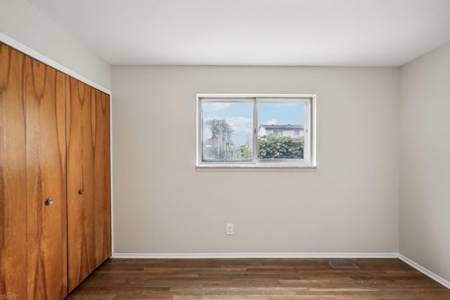 unfurnished bedroom with a closet and dark wood-type flooring