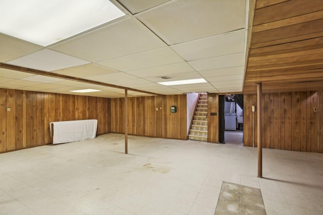 basement with a paneled ceiling and wooden walls