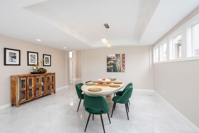 tiled dining space featuring a tray ceiling