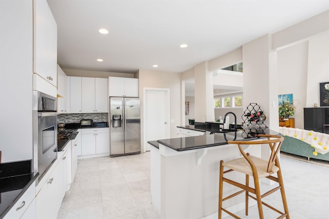 kitchen with light tile patterned floors, white cabinets, a breakfast bar area, appliances with stainless steel finishes, and kitchen peninsula