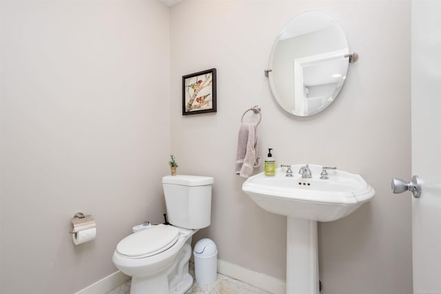 half bath with a sink, toilet, and baseboards