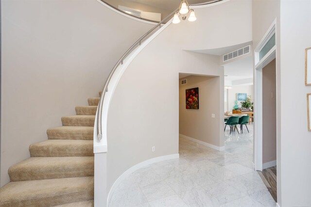 staircase with an inviting chandelier and light tile patterned floors