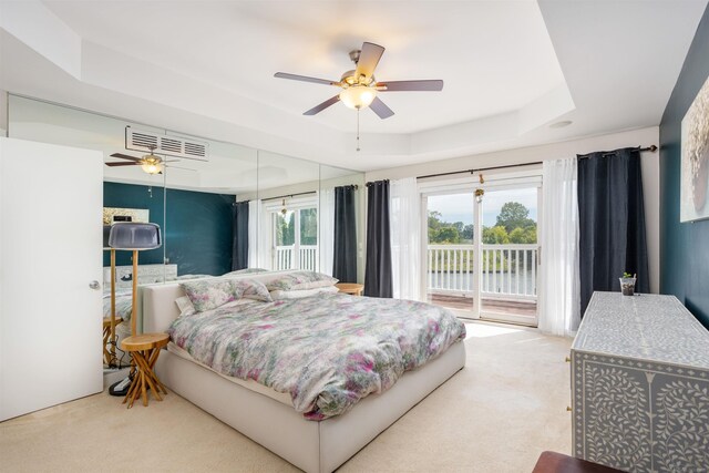 bedroom featuring access to exterior, ceiling fan, carpet, and a tray ceiling