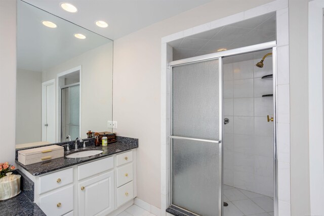 bathroom featuring a shower with shower door, vanity, and tile patterned floors