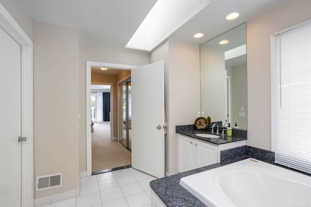 bathroom featuring a skylight, tile patterned floors, a bathing tub, and vanity