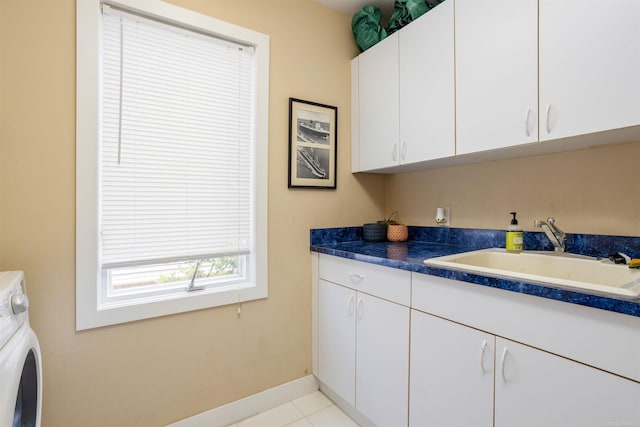 clothes washing area with light tile patterned floors, washer / clothes dryer, cabinet space, a sink, and baseboards