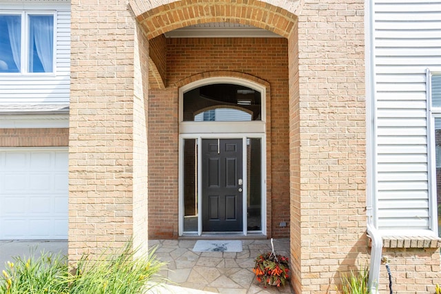 property entrance featuring a garage and brick siding