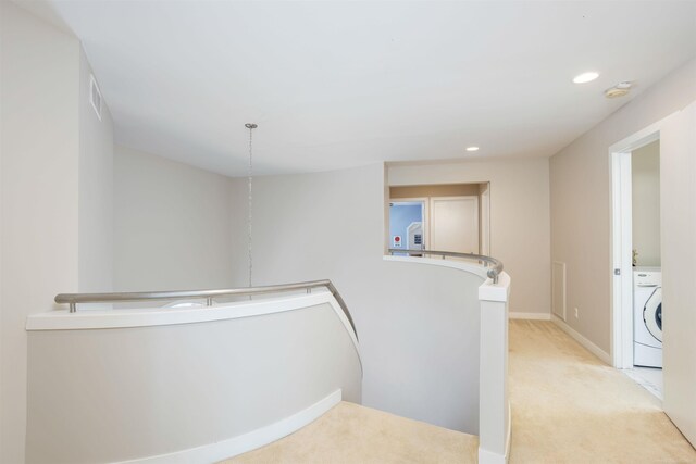 hallway with light carpet and washer / clothes dryer