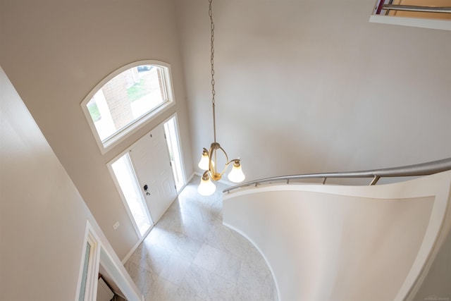 entryway featuring a notable chandelier, a towering ceiling, and baseboards