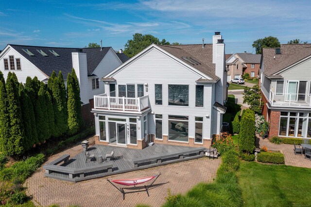 rear view of property featuring a balcony, a wooden deck, and a patio area