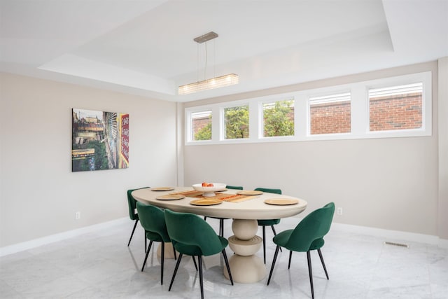 dining space with a raised ceiling, visible vents, and baseboards