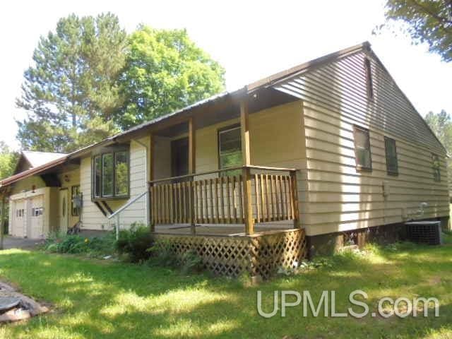 view of side of home featuring a yard, central AC unit, a porch, and a garage