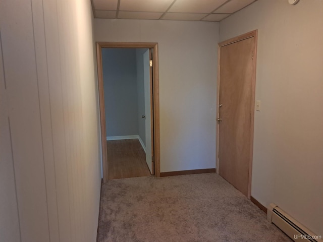 hallway with light carpet, a paneled ceiling, and baseboard heating