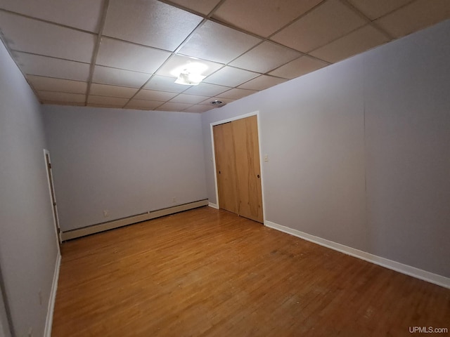 spare room featuring a drop ceiling, a baseboard heating unit, and light hardwood / wood-style flooring