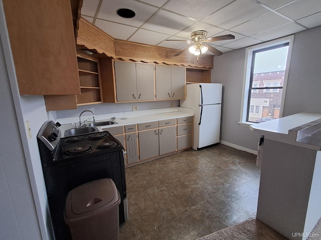 kitchen featuring sink, black range with electric cooktop, white fridge, ceiling fan, and a drop ceiling