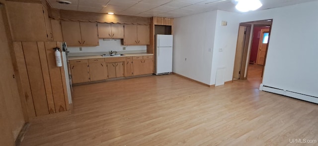 kitchen with sink, light hardwood / wood-style flooring, baseboard heating, and white fridge