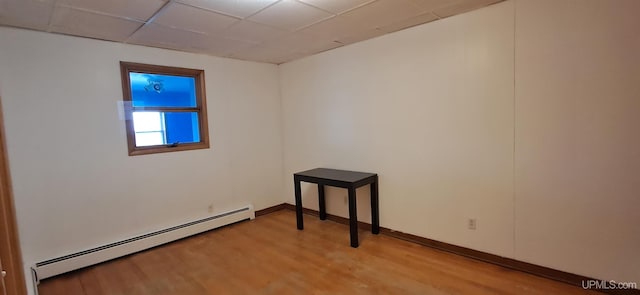 spare room featuring baseboard heating, a paneled ceiling, and light hardwood / wood-style flooring