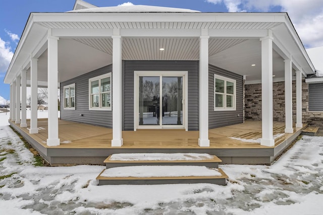 snow covered rear of property with covered porch