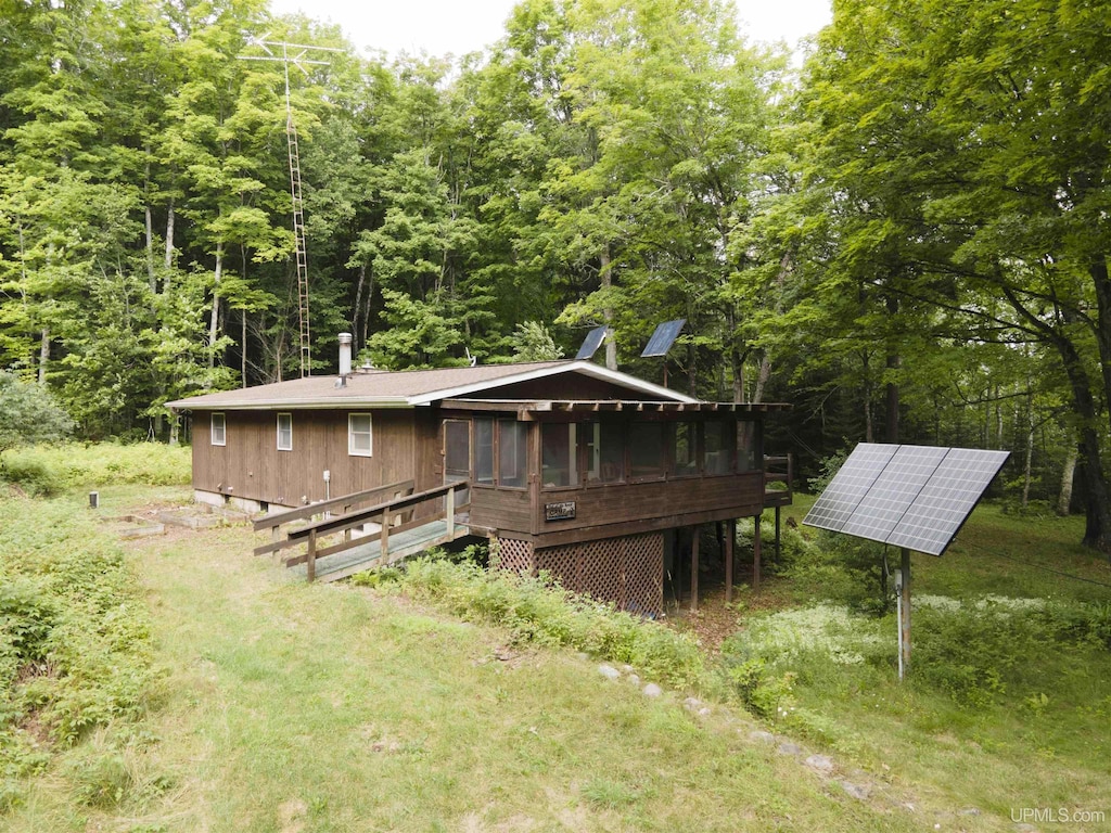 exterior space with a sunroom and solar panels