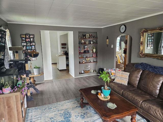 living room with built in shelves, wood-type flooring, and crown molding