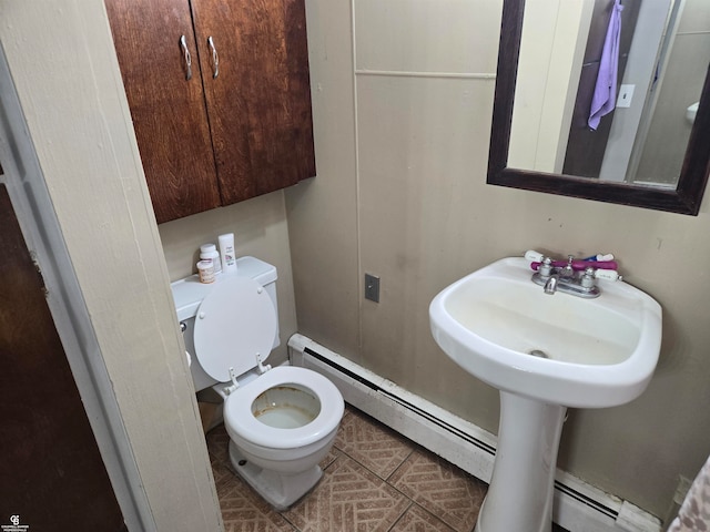 bathroom with toilet, a baseboard heating unit, and sink