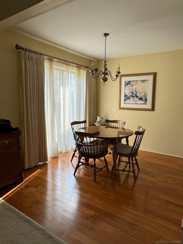 dining space with hardwood / wood-style flooring and an inviting chandelier