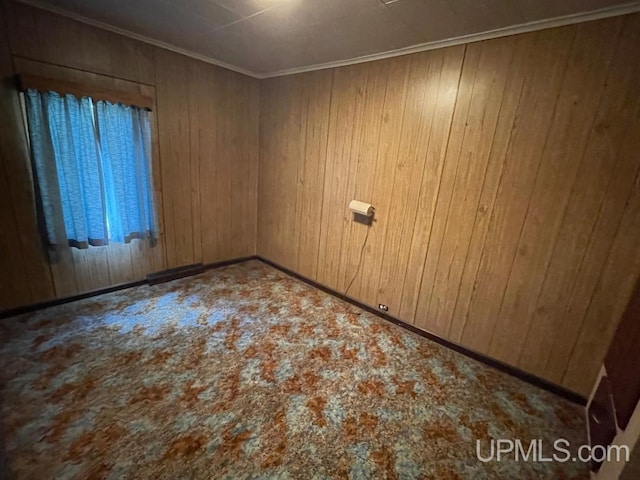 carpeted spare room with crown molding and wood walls