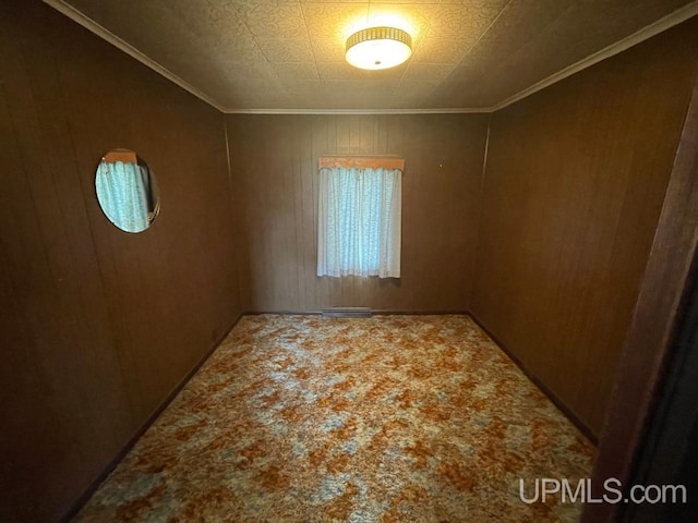 unfurnished room with crown molding and wooden walls