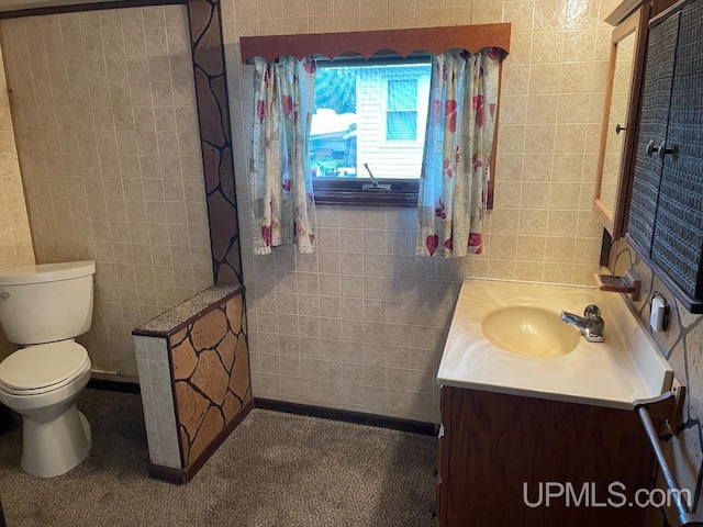 bathroom featuring tile walls, vanity, and toilet