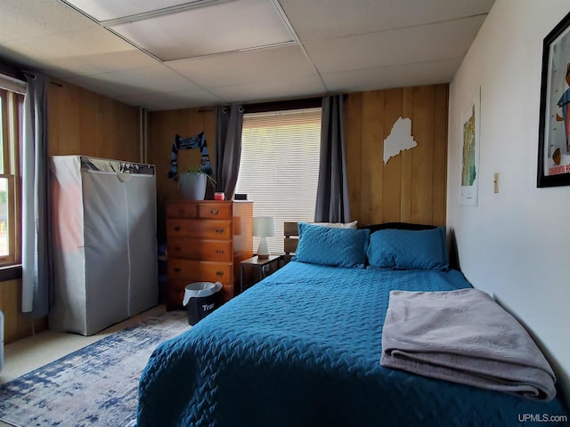 bedroom featuring a drop ceiling and wood walls