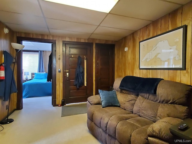 carpeted home theater featuring wood walls and a paneled ceiling