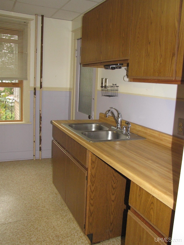 kitchen featuring brown cabinets, a drop ceiling, and a sink