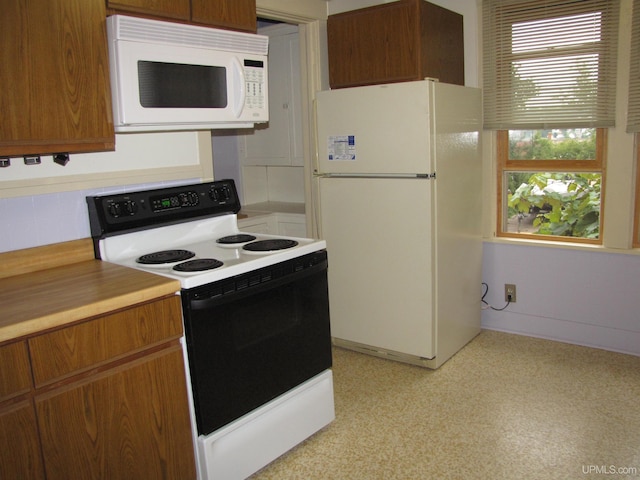 kitchen with brown cabinets, white appliances, and light countertops