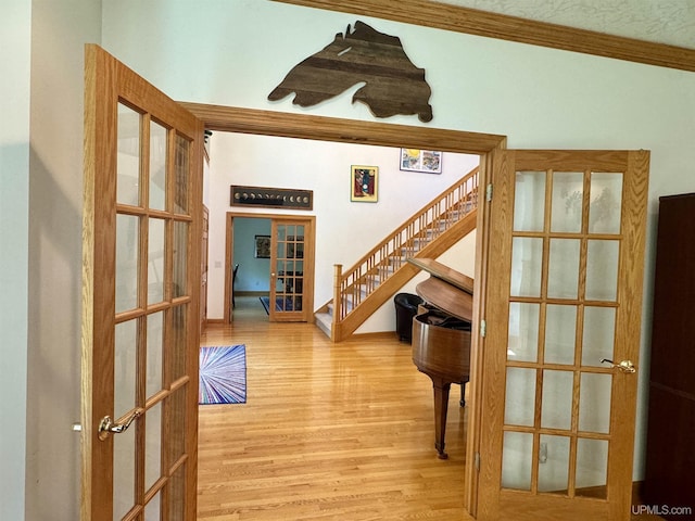 interior space with french doors, wood finished floors, crown molding, and stairway