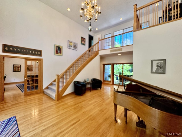 living room featuring an inviting chandelier, stairway, wood finished floors, and a high ceiling