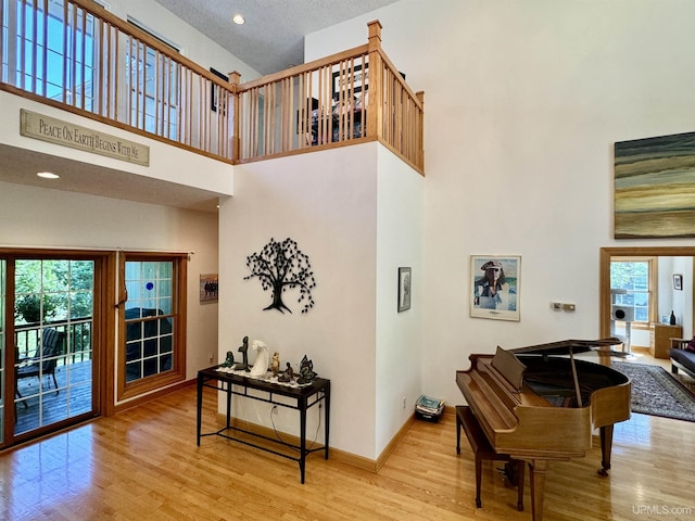 entrance foyer featuring baseboards, a high ceiling, a healthy amount of sunlight, and wood finished floors