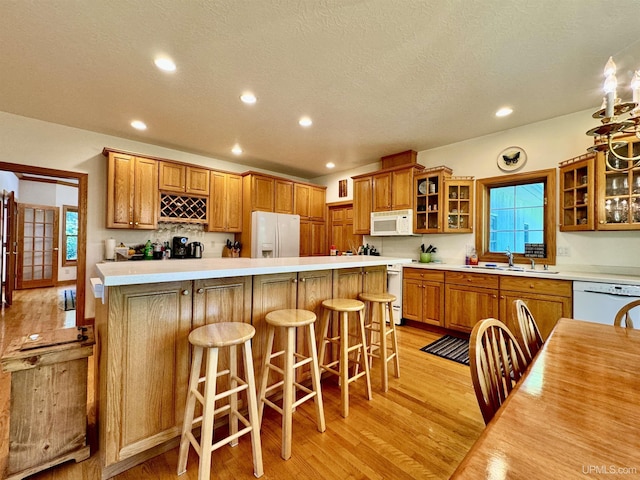 kitchen featuring white appliances, brown cabinets, light wood finished floors, and a sink