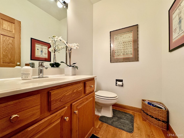 bathroom featuring vanity, toilet, wood finished floors, and baseboards