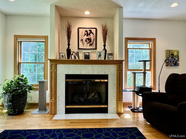 interior space featuring a textured ceiling, a healthy amount of sunlight, wood finished floors, and a tiled fireplace