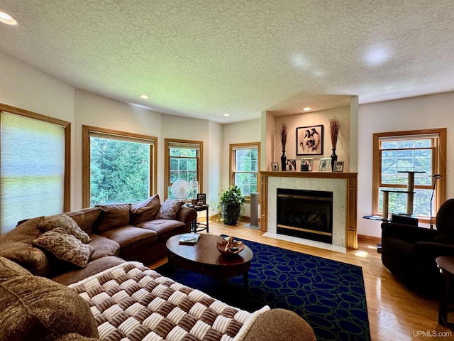 living room featuring recessed lighting, a fireplace, a textured ceiling, and wood finished floors