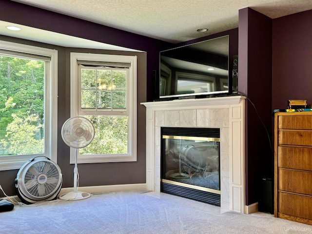 unfurnished living room featuring visible vents, a textured ceiling, carpet, a premium fireplace, and baseboards